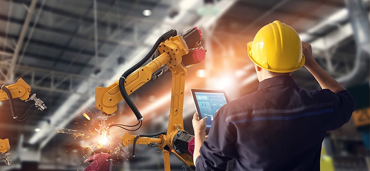 Engineer using tablet check and control automation robot arms machine in intelligent factory industrial on monitoring system software. Welding robotics and digital manufacturing operation.